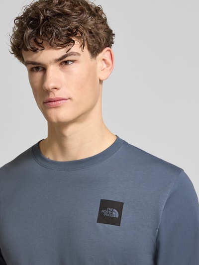 Mannenmodel draagt t-shirt uit katoenmix model 'EVOLUTION' van The North Face, regular fit, ronde hals, labelprint, nahaufnahme bovenlichaam.