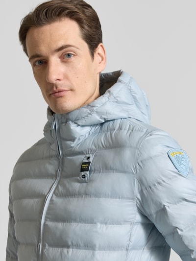 Männermodel trägt hellblaue Steppjacke mit Zweiwege-Reißverschluss Modell 'Charles' von Blauer Usa, Nahaufnahme Oberkörper, Regular Fit, Kapuze, Label-Detail, Größe M.