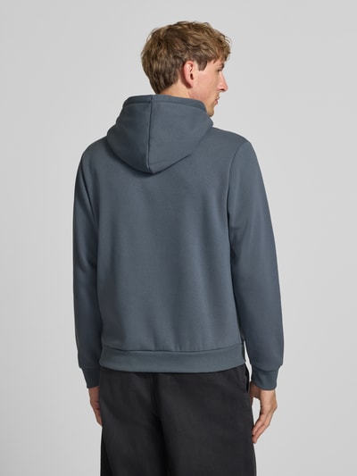 Männermodel trägt Hoodie mit Känguru-Tasche Modell 'BRADLEY' von JACK & JONES in Blau, Baumwoll-Mix, lockerer Schnitt, Ganzkörperansicht Rückansicht.