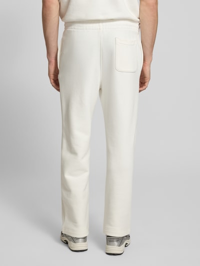 Männermodel trägt Loose Fit Sweatpants aus reiner Baumwolle von Lacoste in Unifarben, elastischer Bund, gerade Beine, Rückansicht Ganzkörperansicht.