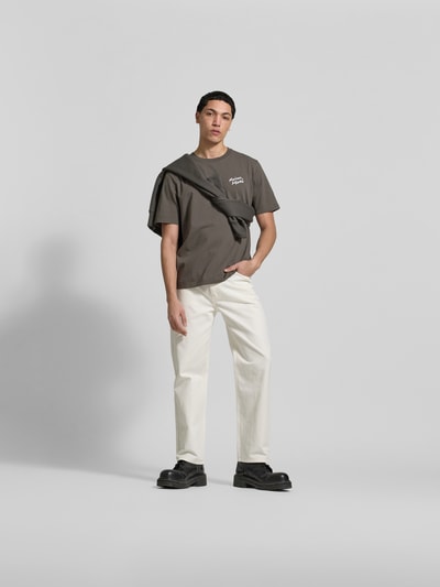 Männermodel trägt Regular Fit T-Shirt aus reiner Baumwolle von MAISON KITSUNÉ in Grau, lockerer Schnitt, weiße Hose, Ganzkörperansicht von vorne.