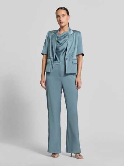 Frauenmodel trägt Wide Fit Hose mit Bundfalten von SWING in Hellblau, taschenloses Design, mit Haken- und Reißverschluss, Ganzkörperansicht von vorne.