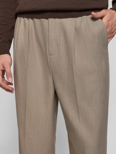 Männermodel trägt Straight Fit Hose mit Viskose-Anteil Modell 'Grant' von Casual Friday, beiger Farbton, Bügelfalten, Nahaufnahme Oberkörper. Elastischer Material-Mix, teilelastischer Bund, Knopf- und Reißverschluss, Kontext: Herren Hose, Bundweite 43 cm, Innenbeinlänge 74 cm.