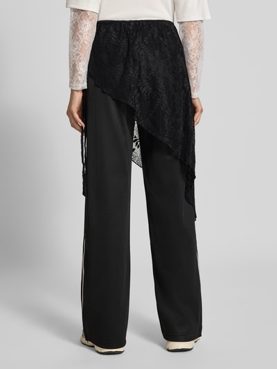 Frauenmodel trägt Loose Fit Sweathose aus Baumwoll-Mix Modell '2IN1 LACE FIREBIRD' von adidas Originals in Schwarz mit Spitze, Ganzkörperansicht Rückansicht. Damen Sweathose von adidas Originals.