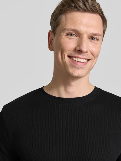 Männermodel trägt T-Shirt mit Rundhalsausschnitt Modell 'ENIL' von Drykorn aus Reine Baumwolle, Slim Fit, schwarz, Nahaufnahme Oberkörper.