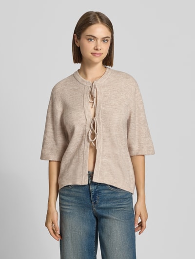 Frauenmodel trägt Regular Fit Strickjacke mit Schnürung Modell 'SIMONI' von ONLY in Beige, kombiniert mit blauen Jeans, Nahaufnahme Oberkörper, Damen Strickjacke von ONLY.