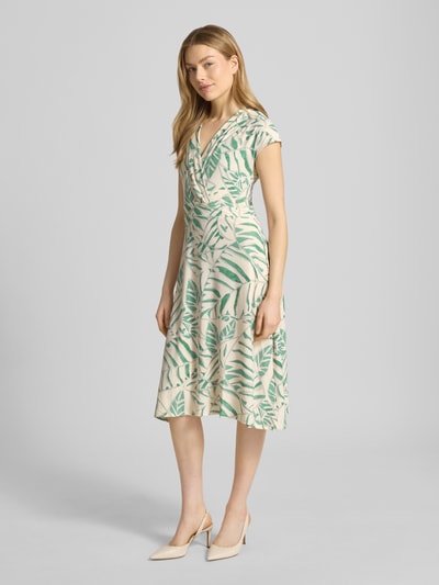 Modelka nosi midikleid w stylu kopertowym z dekoltem V model 'Ca44rrara' od ZABAIONE, beżowo-zielony wzór, rozciągliwy materiał, krój taliowany, długość tyłu w rozmiarze S 105 cm, szerokość w rozmiarze S 45 cm, kapeluszowe rękawy, widok całej sylwetki z przodu