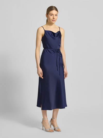 Frauenmodel trägt Slim Fit Midikleid aus Satin Modell 'Thea' von YAS in Dunkelblau, elastischer Material-Mix, Spaghetti-Träger, abnehmbares Taillienband, glatte Oberfläche, Ganzkörperansicht von vorne.