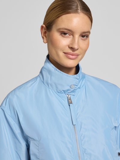 Frauenmodel trägt Jacke mit Zweiwege-Reißverschluss und Stehkragen von Fuchs Schmitt in Hellblau, glatte Textur, Nahaufnahme Oberkörper. Gerader-Schnitt, Eingrifftaschen mit Druckknopfverschluss, elastische Ärmelabschlüsse, Rückenlänge 61 cm, Schulterbreite 49 cm, Brustweite 56 cm, Ärmellänge 56 cm bei Größe 36.