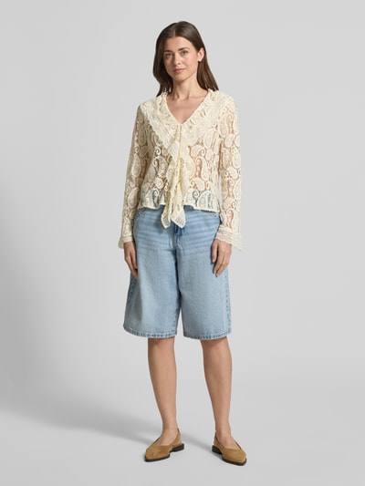 Kobiece modelka nosi bluzkę z długim rękawem Regular Fit Regular Fit aus Baumwoll-Mix model 'SALLY' von Vero Moda, półprzezroczysty materiał, kołnierz z falbanami, abstrakcyjny wzór, głęboki dekolt w serek, listwa guzikowa, długi rękaw, jasne kolory, koronkowa faktura, Ganzkörperansicht von vorne.