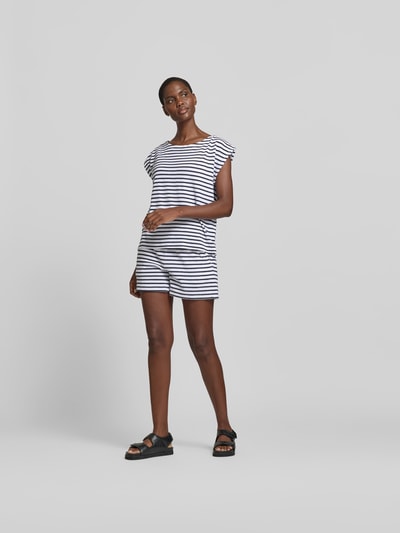 Frauenmodel trägt T-Shirt in Frottee-Optik von Juvia aus Baumwoll-Mix, Relaxed-Fit, Rundhalsausschnitt, Kappärmel, Rückenlänge 56 cm, Ganzkörperansicht von vorne.