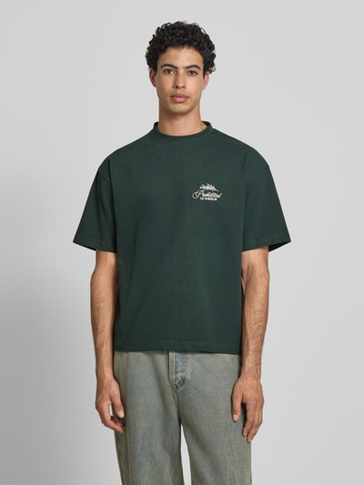 Männermodel trägt T-Shirt mit Label-Stitchings und Rundhalsausschnitt von PROHIBITED in Dunkelgrün, Reine Baumwolle, Regular-Fit, Rückenlänge bei Größe M 65 cm, Ganzkörperansicht von vorne.