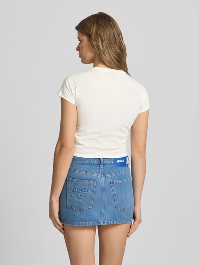 Frauenmodel trägt Slim Fit T-Shirt aus reiner Baumwolle Modell 'DICHROMA_B' von Hugo Blue, Optik: Unifarben, Motiv-Print, Kurzarm, Rundhals, glatte Jersey-Textur, in Weiß, Ganzkörperansicht Rückansicht.