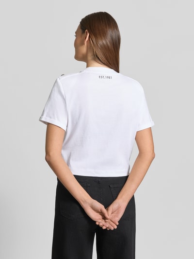Vrouwenmodel draagt Cropped T-shirt met logo model 'MARINA' van Guess, puur katoen, korte look, ronde hals, ruglengte maat S: 45 cm. Ganzkörperansicht Rückansicht.