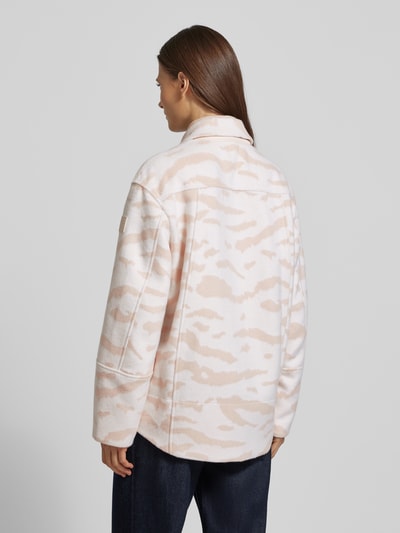 Frauenmodel trägt Jacke mit Stehkragen von Marc Cain aus mieszanka bawełny, krój regular fit, jasne beżowo-białe wzory, długość tyłu 72 cm, szerokość ramion 50 cm, szerokość klatki piersiowej 55 cm, długość rękawów 59 cm, listwa guzikowa, wpuszczane kieszenie, detal z logo, całkowity widok z tyłu.