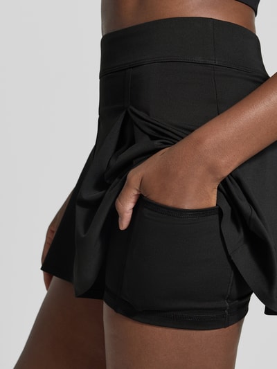 Vrouwenmodel draagt Ausgestellter Sport-Rock met geïntegreerde fietsbroek van Lacoste Sport in zwart, detailopname heup en dij.