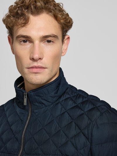 Männermodel trägt Steppjacke mit Stehkragen und Reißverschlusstaschen von Christian Berg Men, dunkelblau, Rautenstruktur, Nahaufnahme Oberkörper. Regular Fit, Reißverschluss, Reißverschlusstaschen, Schulterbreite 48 cm, Brustweite 60 cm, Ärmellänge 69 cm, Rückenlänge 68 cm.