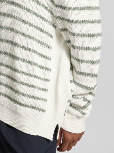Männermodel trägt Strickpullover mit Rundhalsausschnitt von ARMANI EXCHANGE in Weiß mit grünen Streifen, reine Baumwolle, Nahaufnahme Oberkörper.