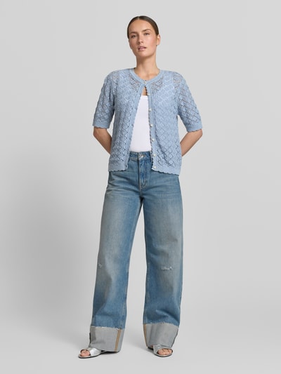 Modelka kobieca ma na sobie Regular Fit Strickjacke aus reiner Baumwolle Modell 'SOFIA' od Selected Femme, jasnoniebieski ajour, okrągły dekolt, krótki rękaw, przód, widok całej sylwetki.