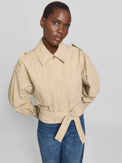 Frauenmodel trägt Jacke aus reiner Viskose Modell 'ZYNIA' von IRO in Beige mit Bindegürtel und Eingrifftaschen, lockere Passform, Ganzkörperansicht von vorne. Rückenlänge 52 cm, Brustweite 52 cm, Ärmellänge 61 cm bei Größe 36.