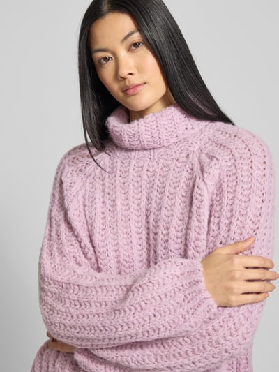 Frauenmodel trägt Strickpullover mit Rollkragen von Smith and Soul in Rosa, lockerer Schnitt, gerippte Abschlüsse, Nahaufnahme Oberkörper.