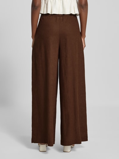 Frauenmodel trägt Wide Fit Leinen-Hose aus Leinen-Mix von Rich & Royal in Braun, elastischer Bund, Bundfalten, Ganzkörperansicht Rückansicht.