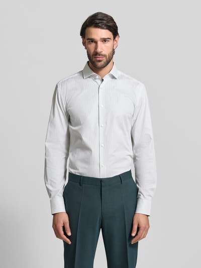 Männermodel trägt Slim Fit Businesshemd aus Baumwoll-Mix Modell 'HANK' von BOSS mit feinen Streifen, Cutaway-Kragen, Ganzkörperansicht von vorne.