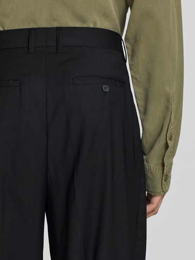 Männermodel trägt Wide Fit Stoffhose aus Woll-Mix von Filippa K, Schwarz mit Gesäßtaschen, Knopf-Reißverschluss, Detailaufnahme Rückansicht.