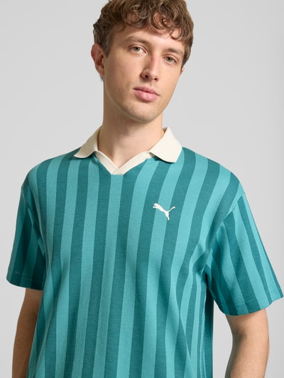 Männermodel trägt Relaxed Fit Poloshirt mit Label-Stitching Modell 'CLASS' von PUMA, gestreifter Baumwoll-Mix in Türkis und Creme, Nahaufnahme Oberkörper.