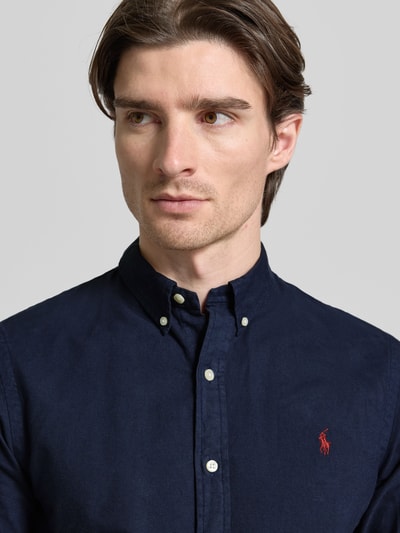 Männermodel trägt Slim Fit Freizeithemd aus reiner Baumwolle von Polo Ralph Lauren in Dunkelblau mit Button-Down-Kragen und Logo-Stitching, Nahaufnahme Oberkörper.