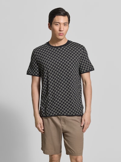 Männermodel trägt T-Shirt mit Logo-Muster und Rundhalsausschnitt von JOOP! Collection aus Baumwoll-Lyocell-Mix, Regular-Fit, Ganzkörperansicht von vorne.