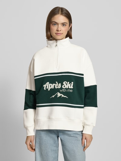Modelka kobieca nosi Relaxed Fit Sweatshirt mit Stehkragen Modell 'Jenny' od LeGer by Lena Gercke, bawełniana mieszanka, z przodu napis, kolor biało-zielony, widok całej sylwetki z przodu.