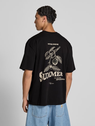 Männermodel trägt Oversized T-Shirt mit Label-Print von Pegador in Schwarz aus Reine Baumwolle, Rückenlänge 72 cm, Ganzkörperansicht Rückansicht.