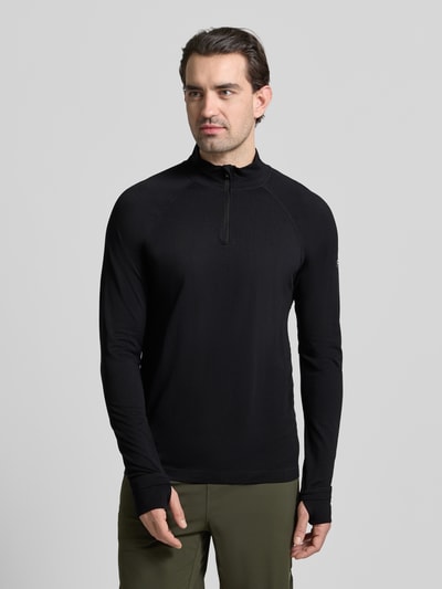 Männermodel trägt Slim Fit Longsleeve mit Logo-Print von Fabletics, Troyer-Kragen, Kinnschutz, schwarz, glatte Textur, Ganzkörperansicht von vorne.
