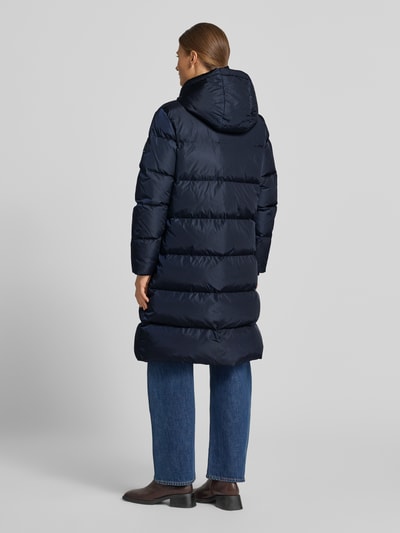 Frauenmodel trägt Steppmantel mit Zweiwege-Reißverschluss von Armani Exchange in Dunkelblau mit Kapuze, Rückenansicht, Ganzkörperansicht Rückansicht. Damen Steppmantel, gerade Passform, Reißverschlusstaschen, Storm Cuffs, Rückenlänge 100 cm, Schulterbreite 43 cm, Brustweite 55 cm, Ärmellänge 63 cm.