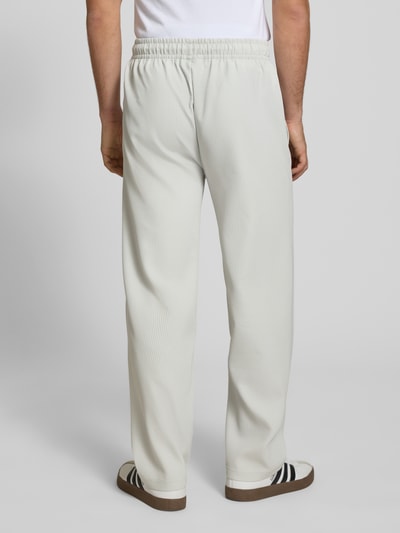 Męski model nosi Sweatpants mit Strukturmuster und elastischem Bund od Pegador, jasny kolor, wzór strukturalny, krój relaxed fit, materiał z domieszką stretchu, długość nogawki wewnętrznej w rozmiarze M: 75 cm, pełny widok sylwetki z tyłu.