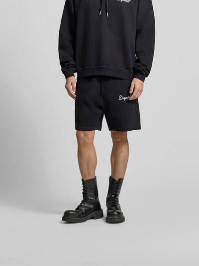 Männermodel trägt Sweatshorts aus reiner Baumwolle von Dsquared2 in Schwarz, gerade Passform, Label-Stitching, Nahaufnahme Unterkörper.