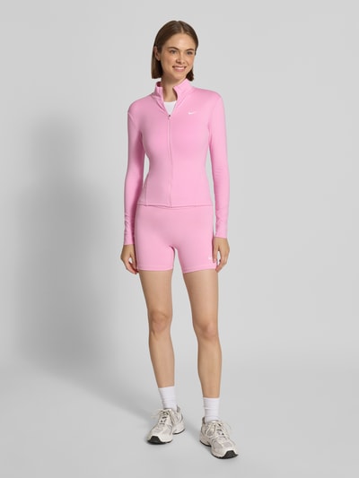 Frauenmodel trägt Slim Fit Trainingsjacke mit Dri-FIT ADV Technology von Nike in Rosa, glatte Textur, Damen Trainingsjacke, Ganzkörperansicht von vorne