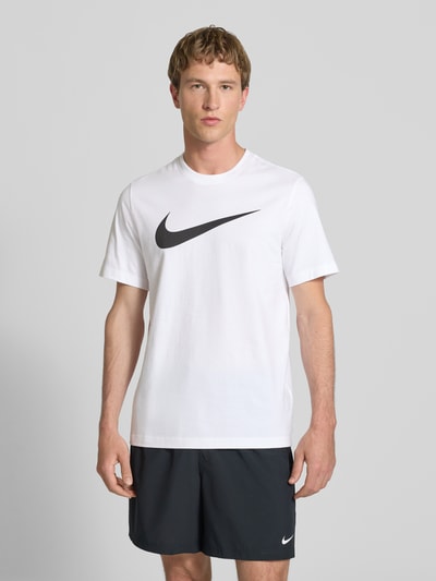 Männermodel trägt Herren T-Shirt mit Logo-Print Modell 'Swoosh' von Nike aus Reine Baumwolle, Gerader-Schnitt, Weiß, Ganzkörperansicht von vorne.