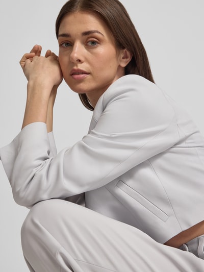 Frauenmodel trägt Asymmetrisch geschnittenen cropped Blazer-curated by Vicky Heiler von SIC aus Viskose-Elasthan-Mix in Hellgrau, Nahaufnahme Oberkörper.
