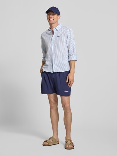 Männermodel trägt Badehose mit Label-Stitching und elastischem Bund von PROHIBITED in Dunkelblau, Regular-Fit, Ganzkörperansicht von vorne, Herren Bademode, Bundweite bei Größe M: 33 cm, Innenbeinlänge: 15 cm.