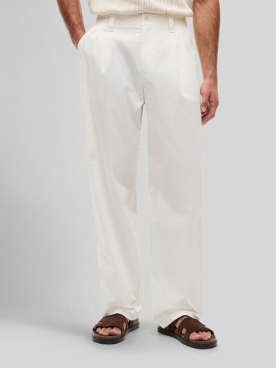 Mężczyzna nosi Loose Fit Hose mit Bundfalten von Tommy Hilfiger, efekt: jednolity kolor, krój loose fit, materiał: czysta bawełna, zakładka w pasie, wpuszczane kieszenie z przodu, kieszeń z patką z tyłu, zapięcie na guzik, spodnie materiałowe, Ganzkörperansicht von vorne.