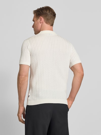 Männermodel trägt Strickshirt mit Polokragen Modell 'Tristao' von JOOP! Collection in Weiß, Reine Baumwolle, Slim-Fit, Ganzkörperansicht Rückansicht.