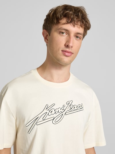 Męski model nosi Oversized T-Shirt mit Logo-Stitching od KARL KANI, czysta bawełna, krój oversized fit, logo, okrągły dekolt, ujęcie z przodu, zbliżenie na górną część ciała.