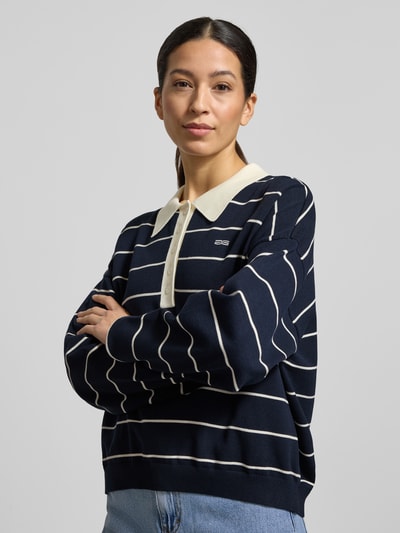 Frauenmodel trägt Strickpullover mit Polokragen Modell 'taige' von Gestuz, dunkelblau mit weißen Streifen, Oversized, Nahaufnahme Oberkörper.