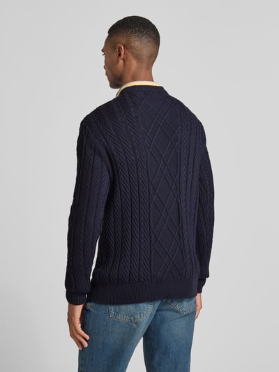 Männermodel trägt Strickpullover aus Baumwoll-Modal-Mix von Guess in Dunkelblau, Zopfmuster, Regular Fit, Rückenansicht, Ganzkörperansicht Rückansicht.