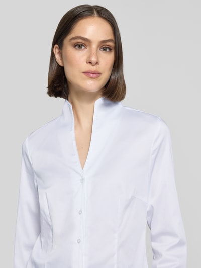 Kobiece modelka nosi bluzka koszulowa 'Hemdbluse mit Stehkragen und V-Ausschnitt' von Christian Berg Woman, mieszanka bawełny z dodatkiem streczu, taliowany krój, stójka, dekolt w serek, listwa guzikowa, długość tyłu w rozmiarze 38: 62 cm, długość rękawów w rozmiarze 38: 62 cm, biała, gładka faktura, widok na górną część ciała z przodu