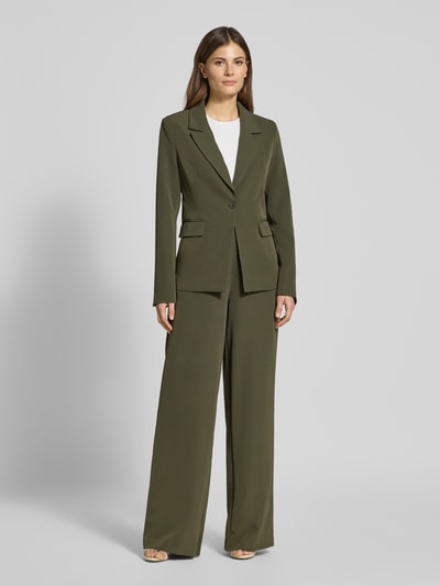 Frauenmodel trägt Slim Fit Blazer mit Pattentaschen Modell 'ISA' von Guido Maria Kretschmer WOMAN in Oliv, Material-Mix mit Stretch-Anteil, Reverskragen, Ganzkörperansicht von vorne