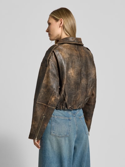 Frauenmodel trägt Lederjacke mit Reißverschlusstaschen Modell 'diana' von Gestuz aus Lammleder und Loose-Fit, Kentkragen, seitlicher Reißverschluss, Pattentaschen, braune Vintage-Optik, Ganzkörperansicht Rückansicht.
