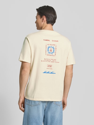 Mężczyzna nosi T-Shirt mit Label-Print Modell 'GERGEI' od Samsøe Samsøe z czystej bawełny, krój relaxed fit, kremowy, nadruk na plecach, całkowity widok z tyłu.